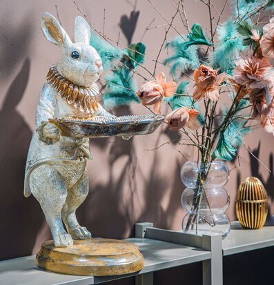 Bild: Kaninfigur med fat och vas med fjädrar, rosa vägg