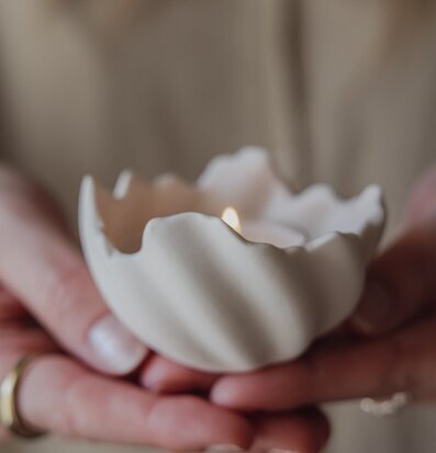 Foto: Ljus i vit skålformad hållare i händerna