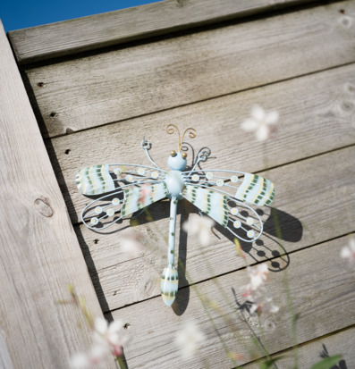 Foto: Väggdekoration trollslända i metall på träfasad