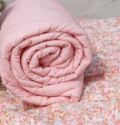 Foto: Rosa/vit randig pläd på blommigt quiltat täcke