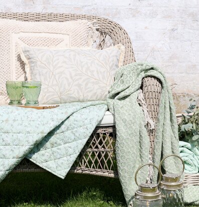 Bild: Rottingsoffa med grön pläd och lyktor uteplats