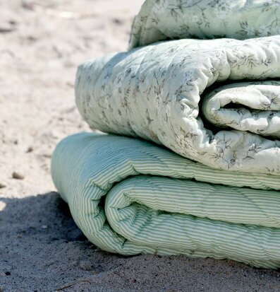 Foto: Quiltade plädar grön/vit på strand i solljus