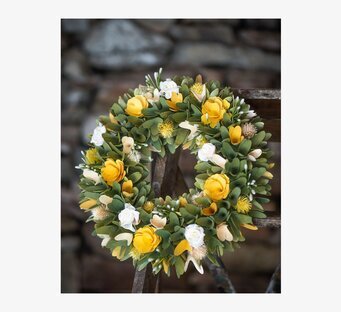 Foto: Blomsterkrans med gula rosor på rustikt trä