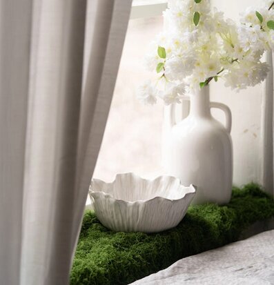 Foto: Vit keramikskål på mossa i fönster med vas
