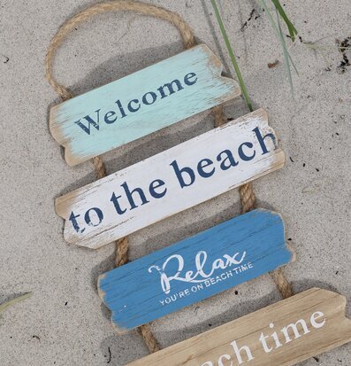 Foto: Welcome-skylt i trä på sand med strandkänsla