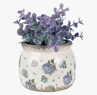 Foto av cremefärgad kruka med blå blommor och växt