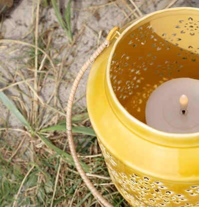 Foto på gul emaljlykta med perforerat mönster, ljus