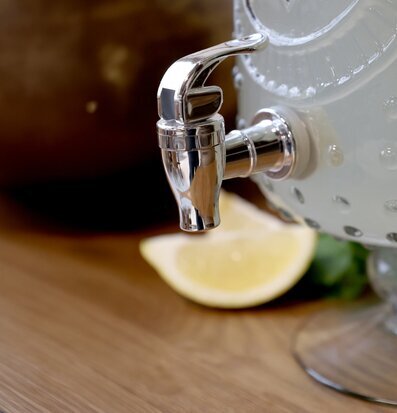 Foto på kromad tappkran på dryckesbehållare, citron