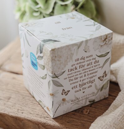 Foto av presentförpackning med botaniskt mönster på träbord