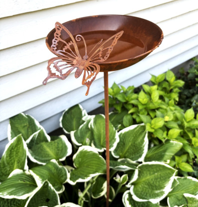 Foto: Rostigt fågelbad med fjäril i lummig rabatt