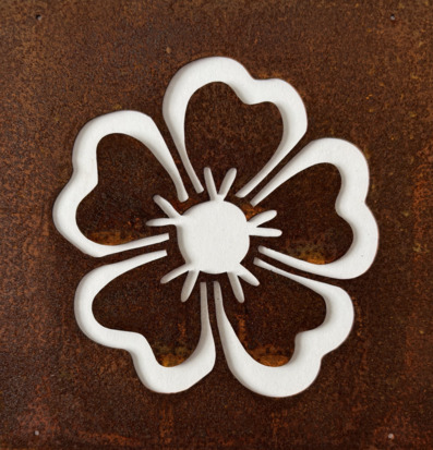 Foto på rostig metallplåt med utskuren blomma närbild