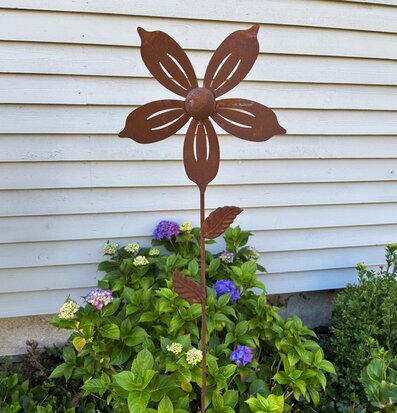 Bild: Rostig metallblomma som vindsnurra vid fasad
