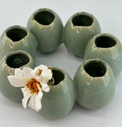 Foto: Grön keramikvas-krans med vit blomma ovanifrån