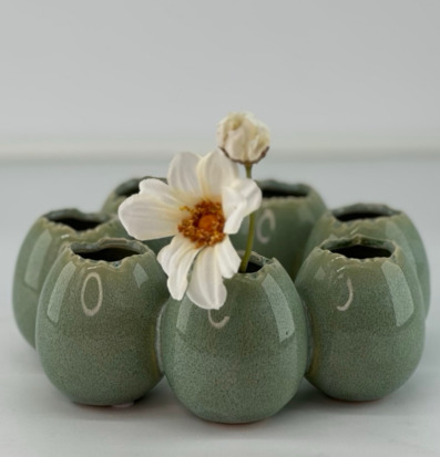 Foto: Grön keramikvas-krans med vit blomma i mitt﻿