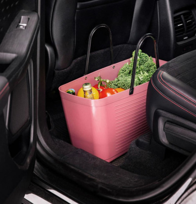 Foto: Varmrosa plastväska med matvaror i bilinteriör