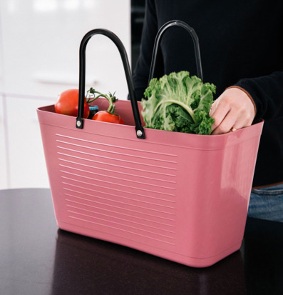 Bild på varmrosa plastväska med grönkål och tomater