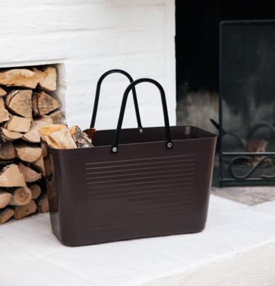 Foto: Brun plastväska med ved vid öppen spis interiör