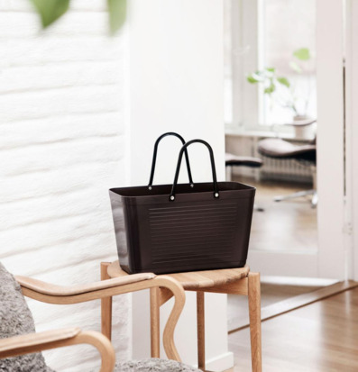 Foto: Brun plastväska på litet träbord vid fönster