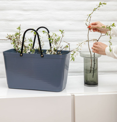 Foto: Duvblå väska med grenar och glasvas inomhus