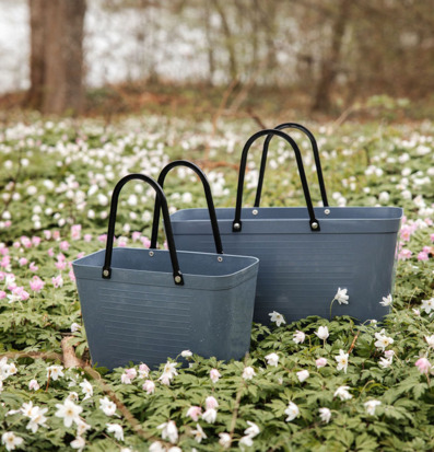 Foto: Duvblå plastväskor i skogsglänta med blommor