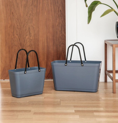 Foto: Duvblå plastväskor på trägolv i interiörmiljö