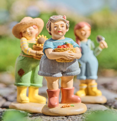 Bild på trädgårdsfigurer med grönsakskorg i solljus