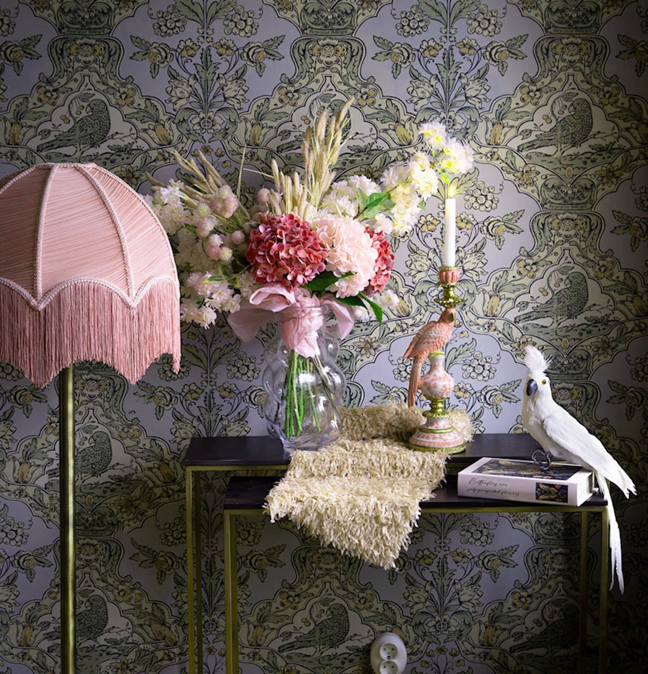 Foto: Rosa franslampa och blommor mot tapetmönster