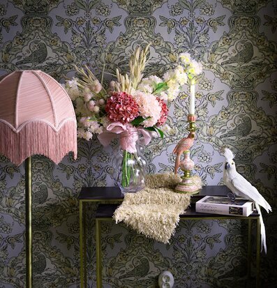 Foto: Rosa franslampa och blommor mot tapetmönster