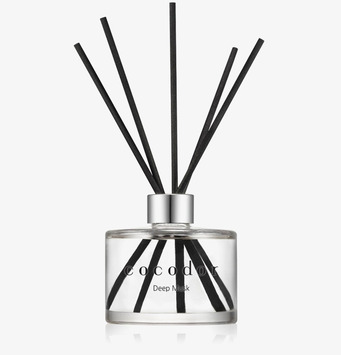 Foto: Doftpinnar i glasflaska med svartpinnar, vit bakgrund