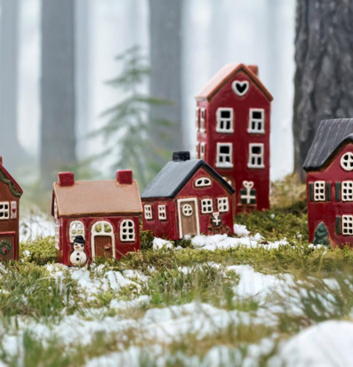 Foto vinterby med huslyktor i snö och mossa skogsvy