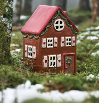 Foto: Husformad ljuslykta i skogsmiljö med snöfläckar