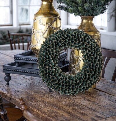 Foto: Grön glitterkrans och guldfärgade vaser i ljus miljö
