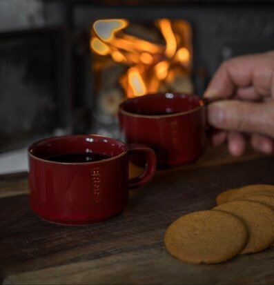 Foto: Röda muggar med glögg och pepparkakor vid eld