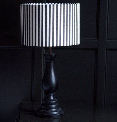 Foto: Randig bordslampa mot svart panelvägg inredning