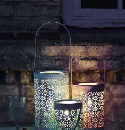 Lykta Garden Grön från Rice i trädgårdsmiljö med tegelvägg