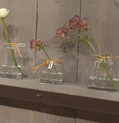 Bild av glaslyktor med ljus och blommor på trähylla