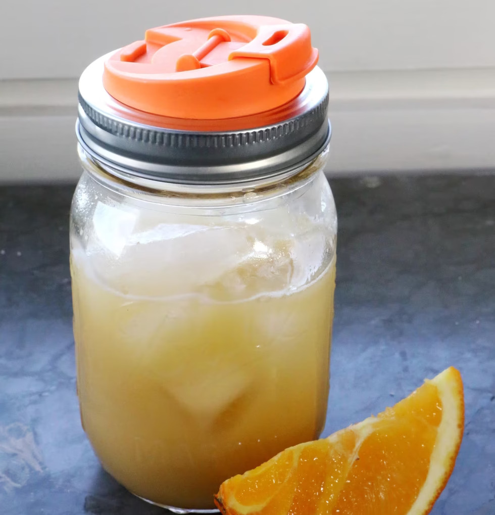 Ball Mason Jar med Drink Lid fylld med blekgul dryck och is