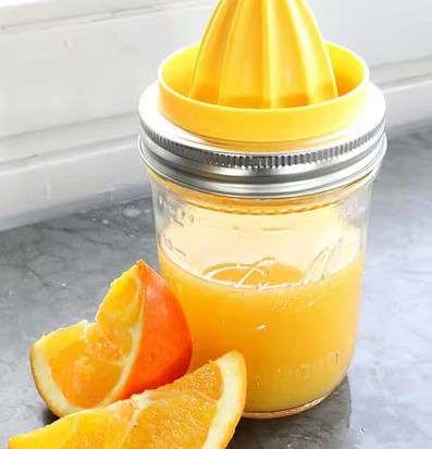 Juicer från Ball Mason Jar på marmoryta med apelsinklyftor