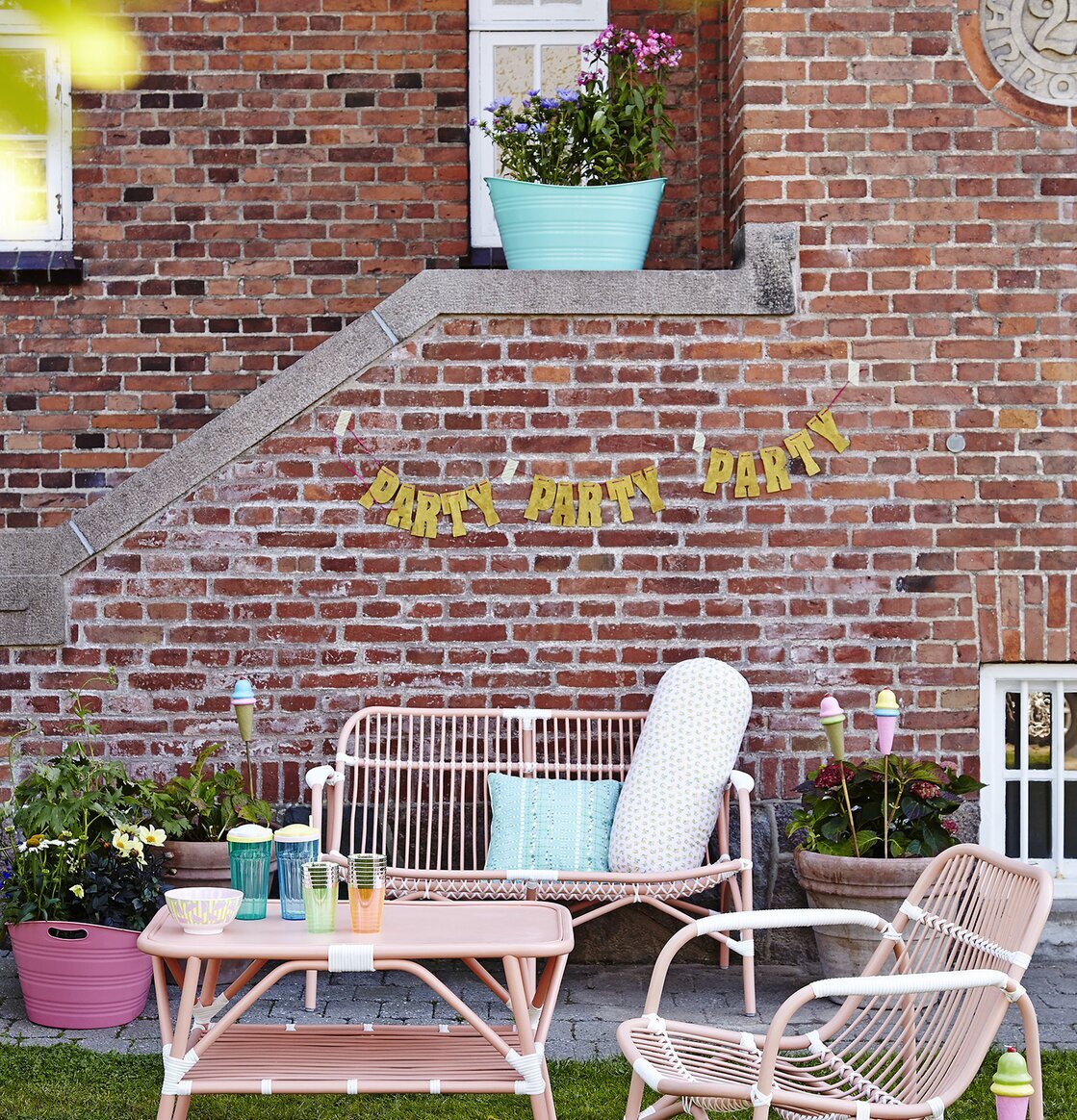 Cane 2 Seater Sofa Soft Coral från Rice i trädgårdsmiljö