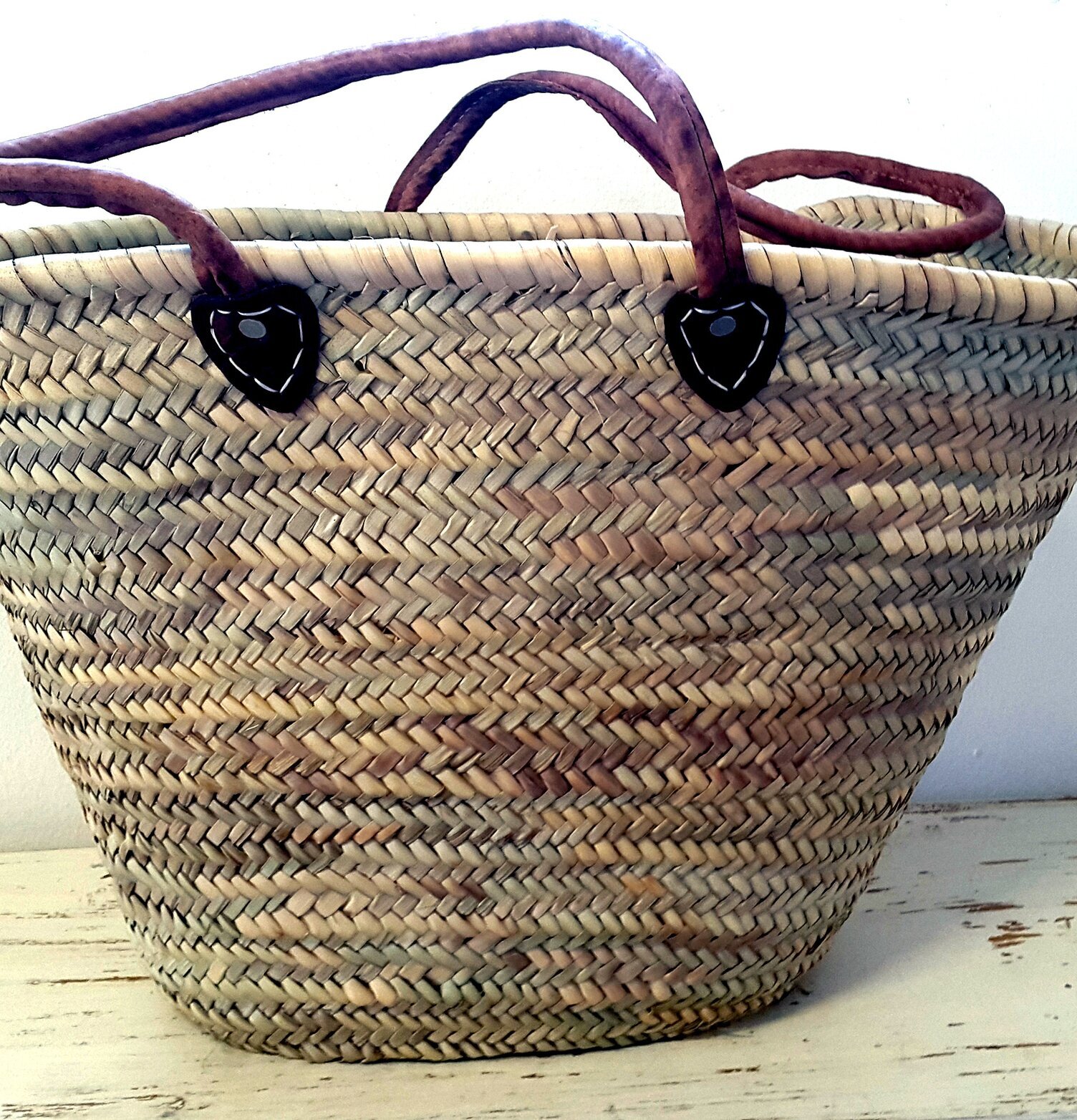 Stråväska från Nomadic Essentials på vitmålad trähylla