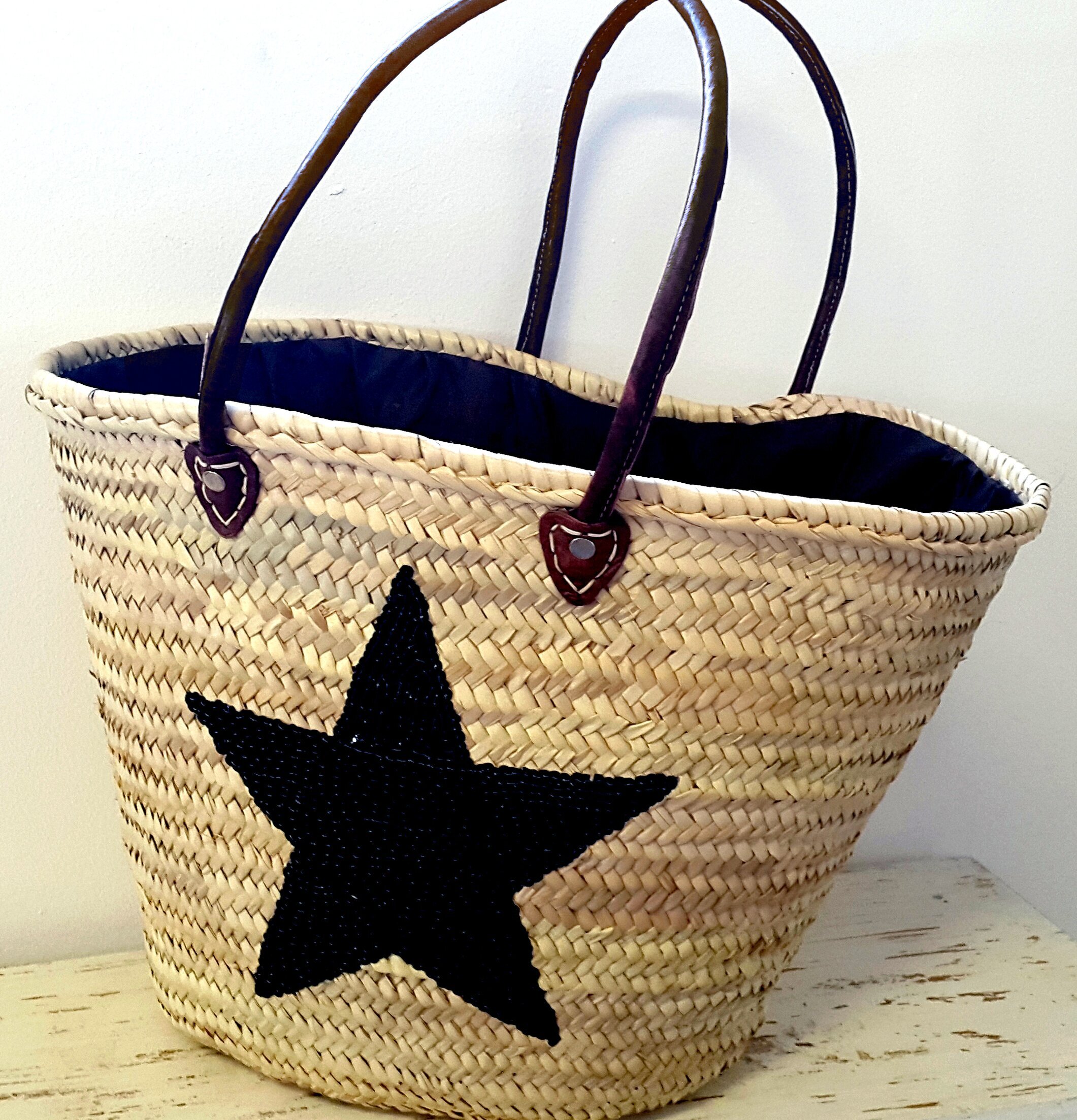 Stråväska Deco Black Star från Nomadic Essentials på träyta