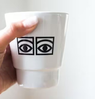 Hand håller Mugg Ögon Cacao 2-Pack från Olle Eksell