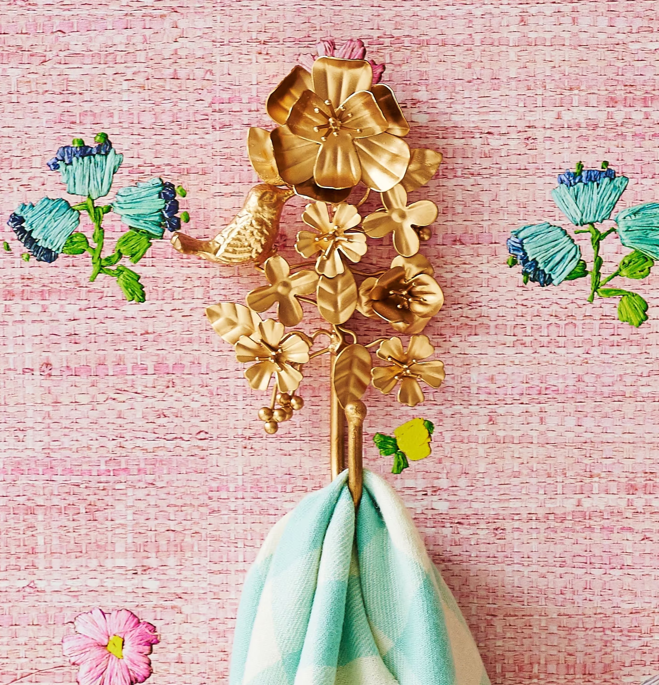 Hängare Guld från Rice med blommor och fåglar mot rosa vägg