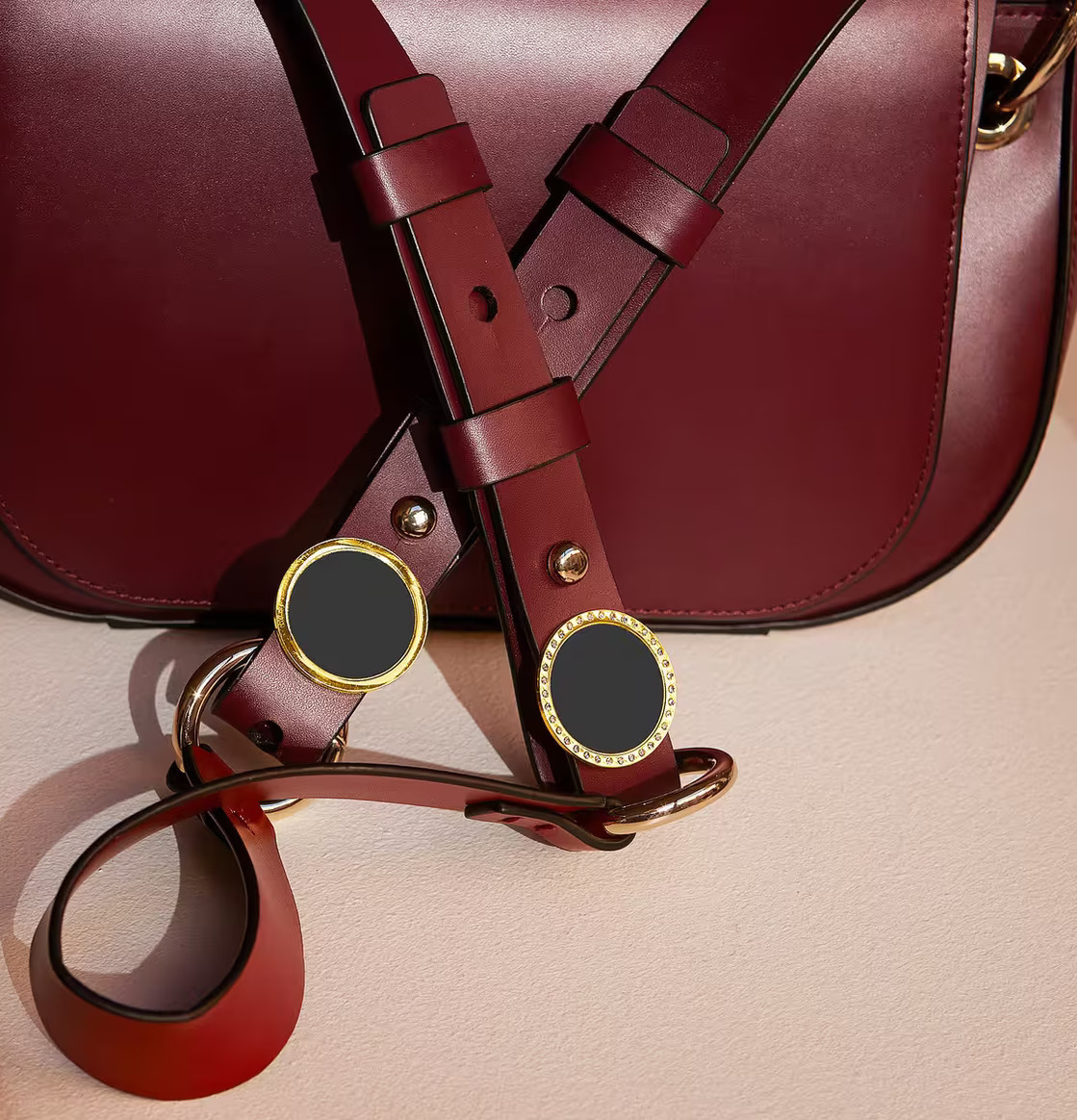 Reflexbrosch Guld Stenar från Firefly på mörkröd läderväska