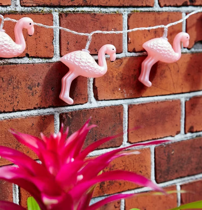 Ljusslinga LED Flamingo från Rice på en röd tegelvägg