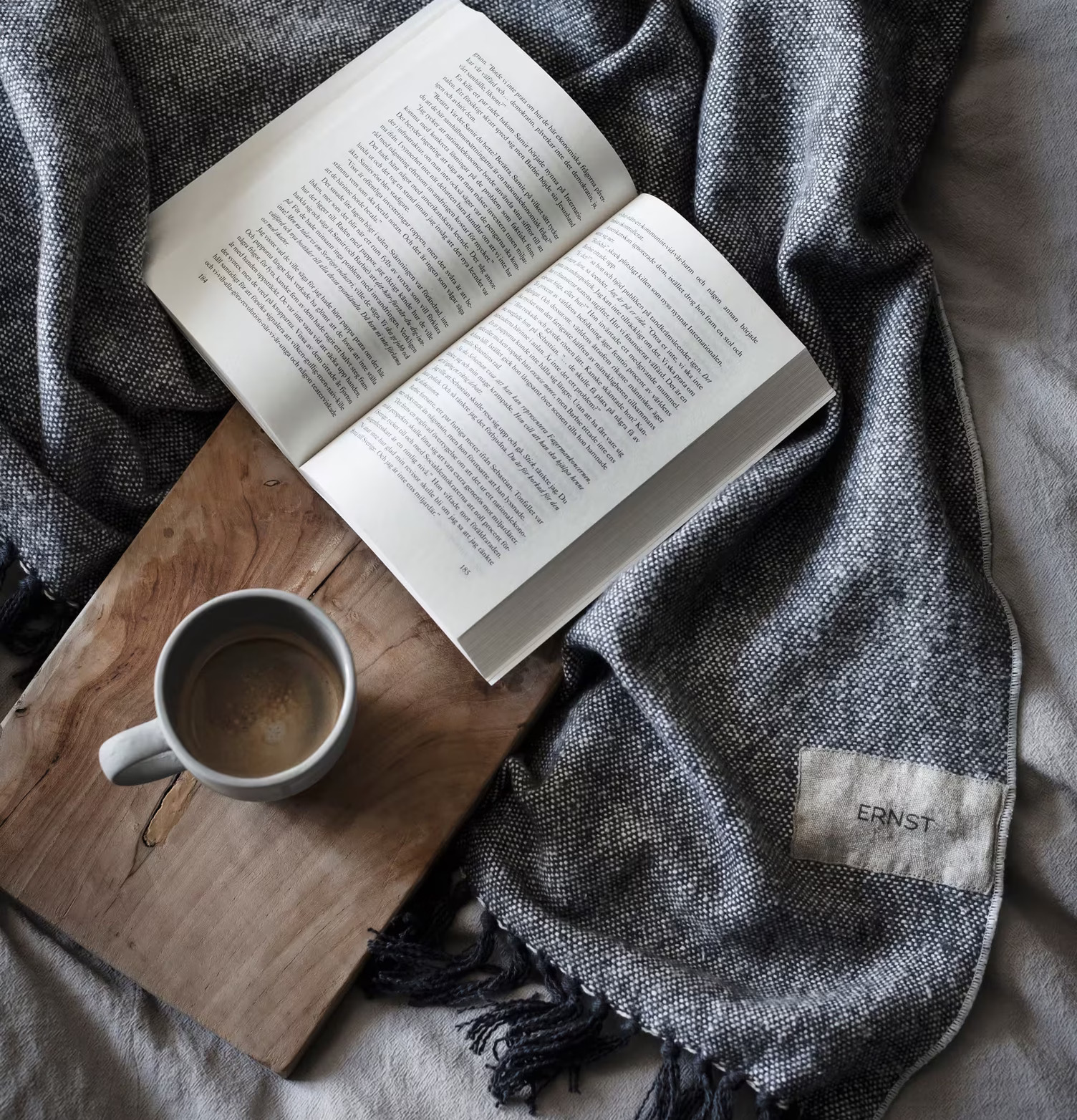 Pläd Bomull Mörkgrå från Ernst på säng med bok och mugg