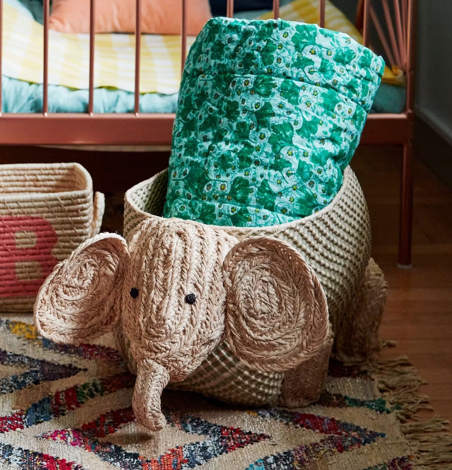 Förvaringskorg Elefant från Rice i rotting, bredvid en säng