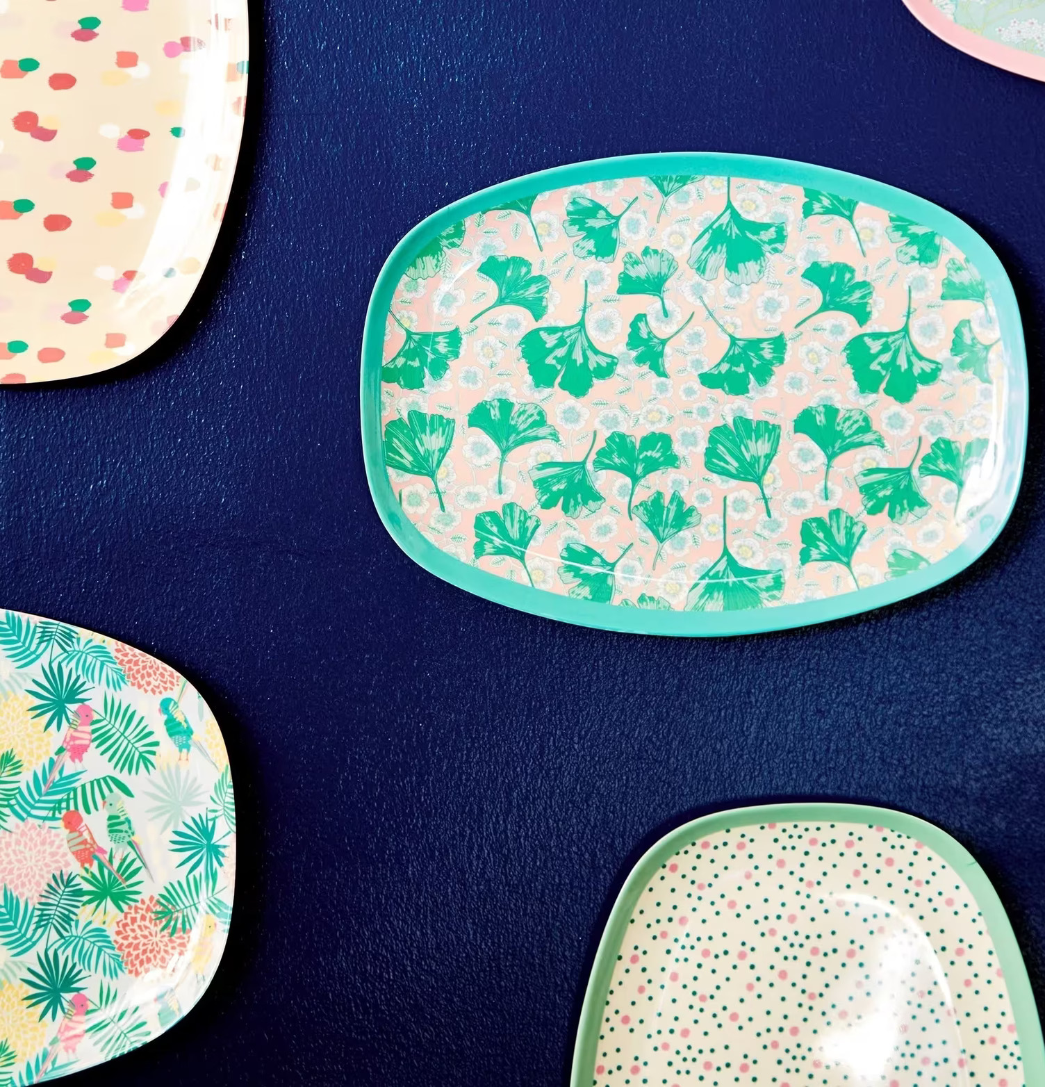 Tallrik Leaves & Flower Print från Rice mot mörkblå vägg