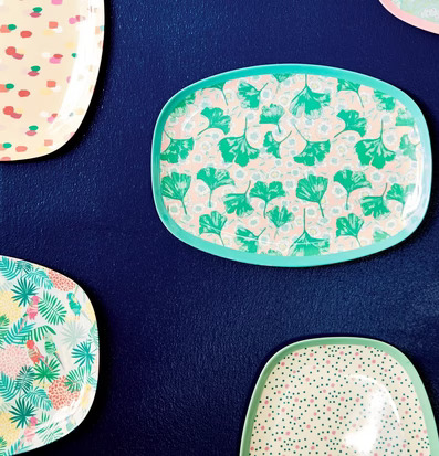 Tallrik Leaves & Flower Print från Rice mot mörkblå vägg